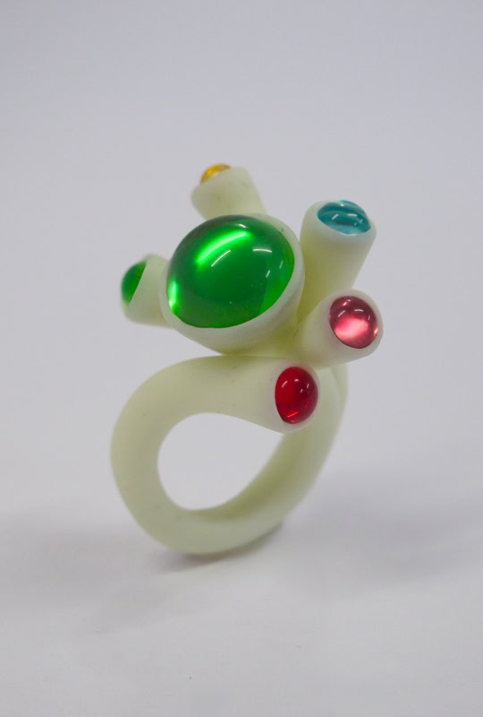 Bague en résine blanc avec des pierres colorées vertes, rouges et bleues.