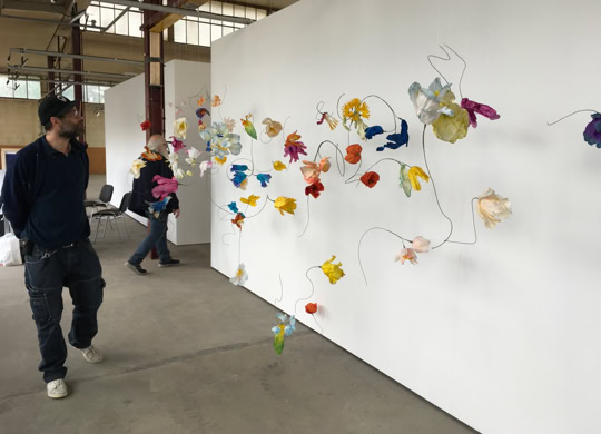Un homme marche à côté d'une installation artistique colorée sur un mur blanc dans une galerie.