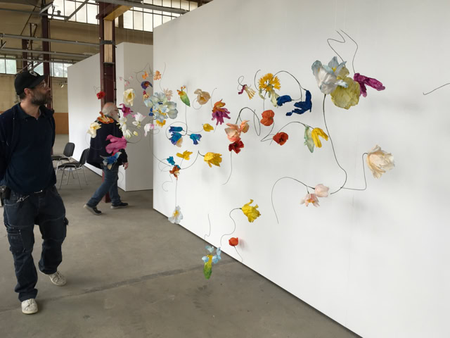 Un homme marche à côté d'une installation artistique colorée sur un mur blanc dans une galerie.