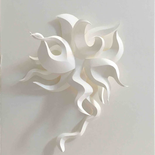 Sculpture en papier blanc avec des formes ondulées et entrelacées sur un fond blanc.