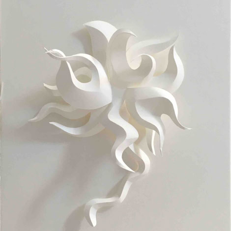 Sculpture en papier blanc avec des formes ondulées et entrelacées sur un fond blanc.
