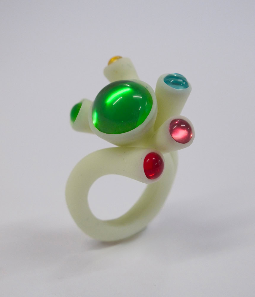 Bague en résine blanc avec des pierres colorées vertes, rouges et bleues.