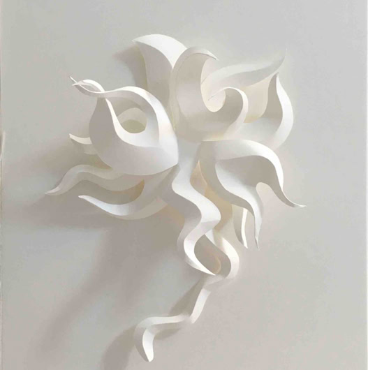 Sculpture en papier blanc avec des formes ondulées et entrelacées sur un fond blanc.