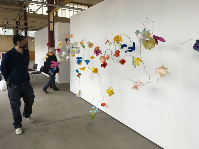 Un homme marche à côté d'une installation artistique colorée sur un mur blanc dans une galerie.