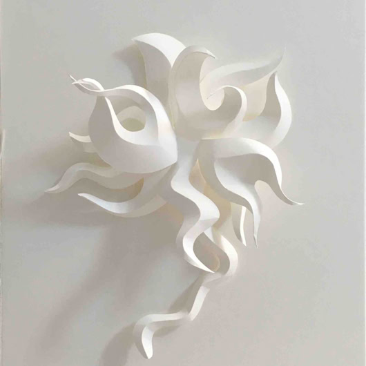 Sculpture en papier blanc avec des formes ondulées et entrelacées sur un fond blanc.