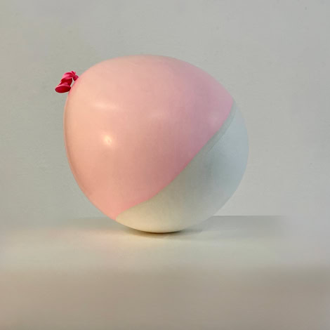 Coquille en plâte et latex d'un ballon bicolore rose et blanc sur une surface blanche.