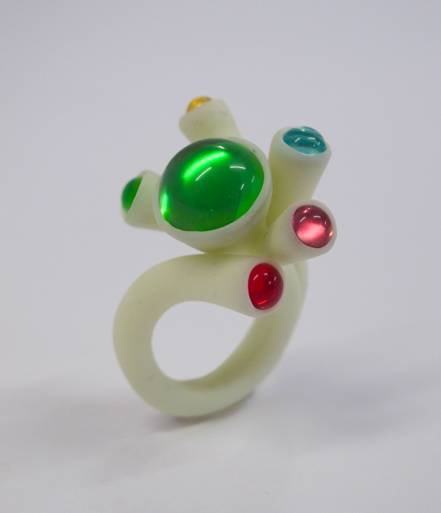 Bague en résine blanc avec des pierres colorées vertes, rouges et bleues.
