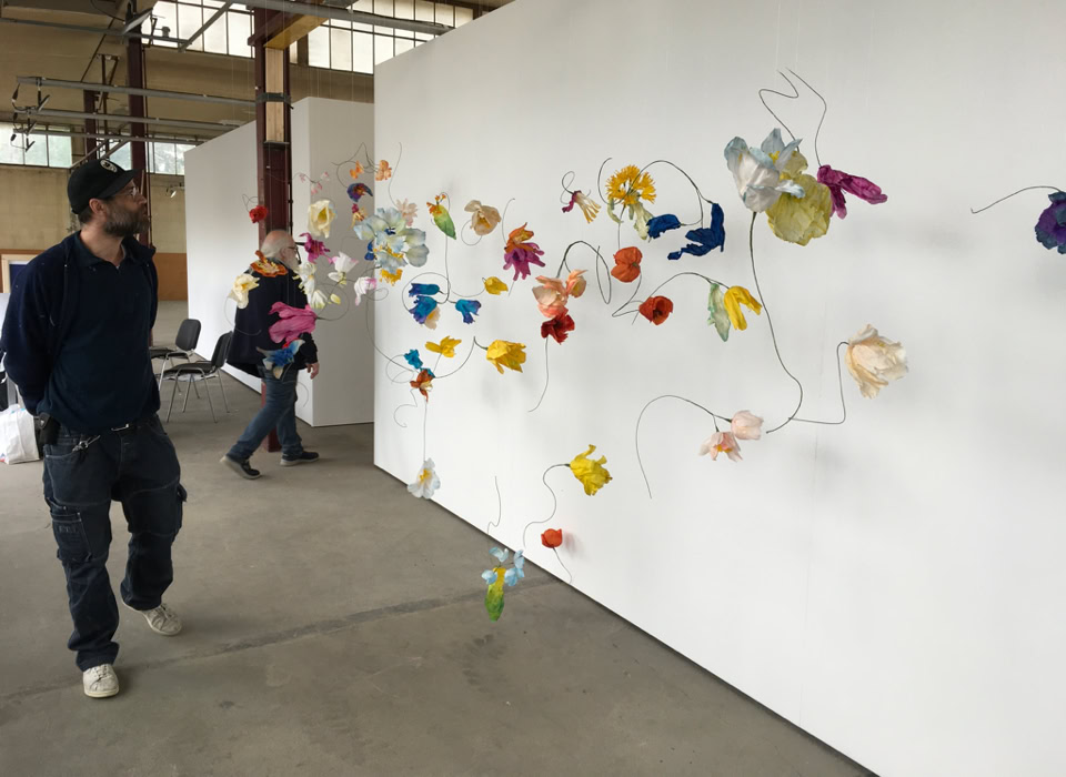 Un homme marche à côté d'une installation artistique colorée sur un mur blanc dans une galerie.