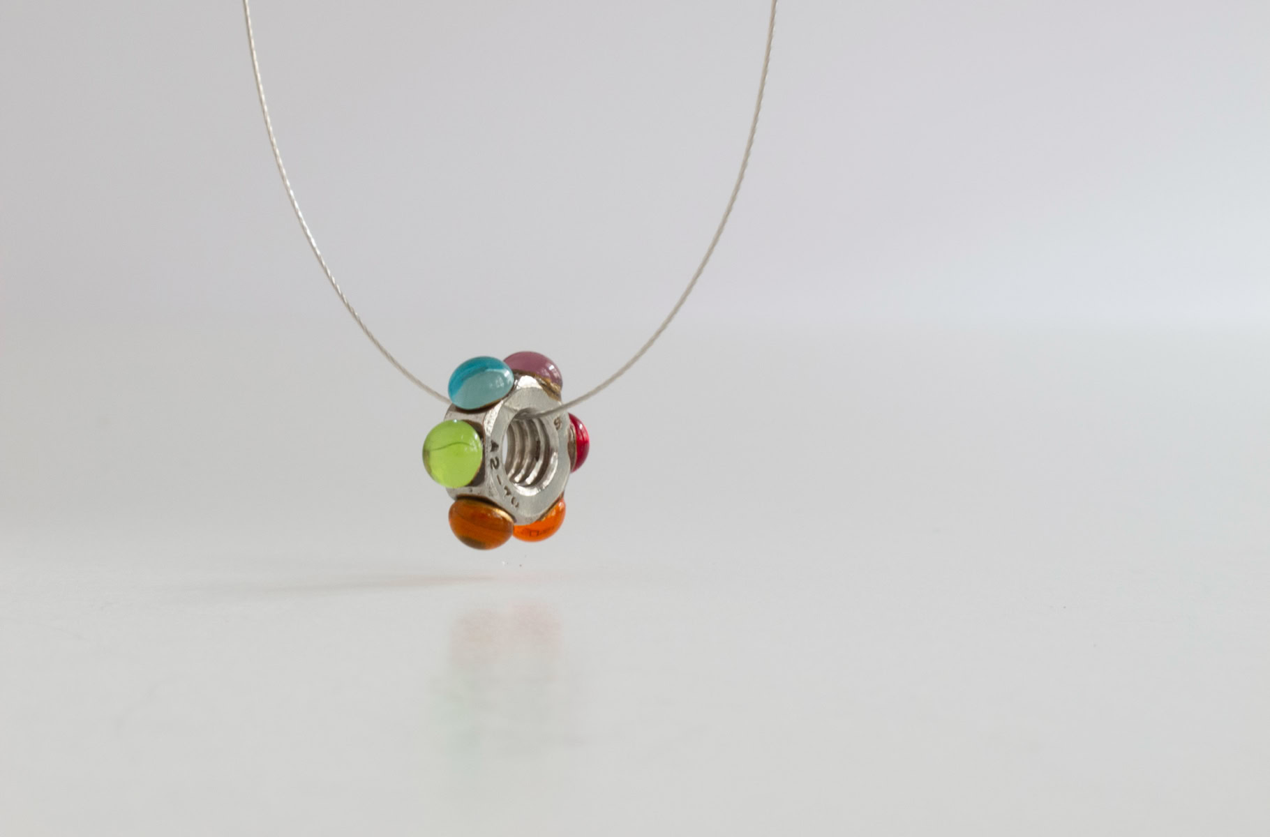 Bague en résine blanc avec des pierres colorées vertes, rouges et bleues.