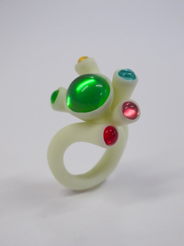 Bague en résine blanc avec des pierres colorées vertes, rouges et bleues.
