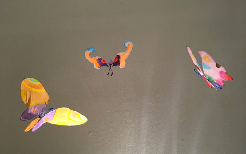 Installation suspendue et poétique de papillons en papier de soie. Dimension 3 m.